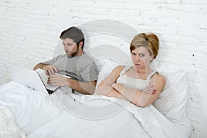 attractive woman feeling upset unsatisfied and frustrated in bed with his husband while the man work on computer laptop ignoring h