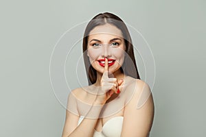 Attractive woman with finger near lips. Secret and silence concept