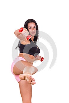 Attractive woman giving a kick with leg lifting dumbbells