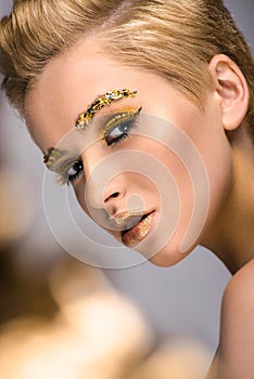 attractive woman with golden glitter on face and short haircut