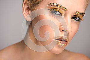 attractive woman with golden glossing glitter on face looking at camera photo