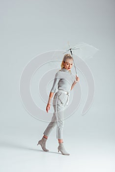 attractive woman in grey clothes posing with transparent umbrella