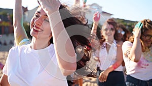 Attractive woman has fun with friends splashing colorful powder, celebrates Holi festival. People play with dry paint at