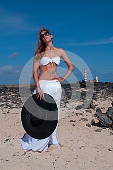 attractive woman with hat in a coastal area and beach in good weather