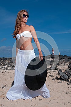 attractive woman with hat in a coastal area and beach in good weather