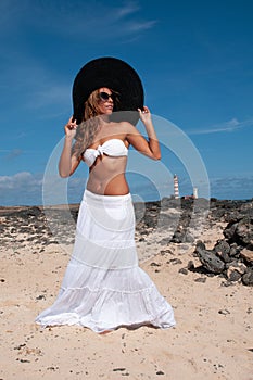 attractive woman with hat in a coastal area and beach in good weather