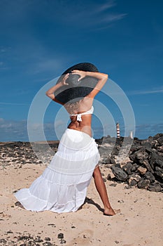 attractive woman with hat in a coastal area and beach in good weather