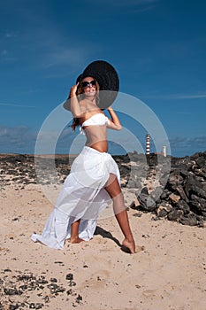 attractive woman with hat in a coastal area and beach in good weather