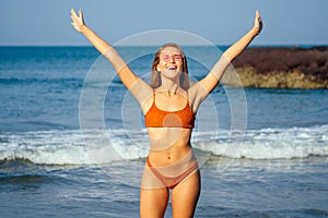 Attractive woman having good time in the beach. young beauty girl wearing coral orange swimsuit bikini bottom with