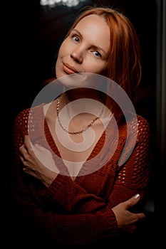 Attractive woman in her forties looking at the camera at home against a dark background