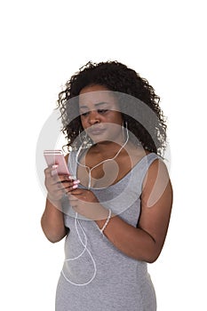 An attractive woman in her twenties wearing ear buds looking at her phone