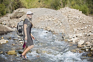 Attractive Woman hiking across a mountain stream