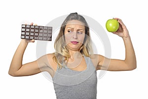 Attractive woman holding apple and chocolate bar in healthy fruit versus sweet junk food temptation