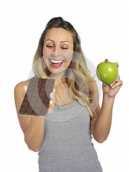 Attractive woman holding apple and chocolate bar in healthy fruit versus sweet junk food temptation