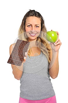 Attractive woman holding apple and chocolate bar in healthy fruit versus sweet junk food temptation