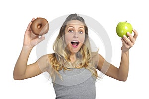 Attractive woman holding apple and chocolate donut in healthy fruit versus sweet junk food temptation