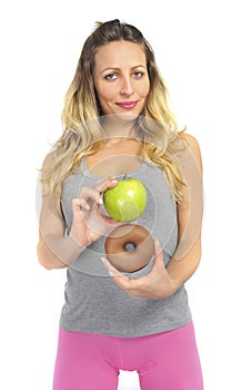 Attractive woman holding apple and chocolate donut in healthy fruit versus sweet junk food temptation