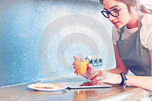 Attractive woman holding a glass of orange juice while standing in the kitchen