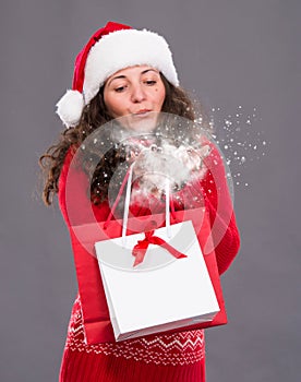 Attractive woman holding shopping bags blowing snow