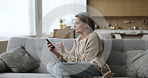 Attractive woman holds modern smartphone rest on sofa at home