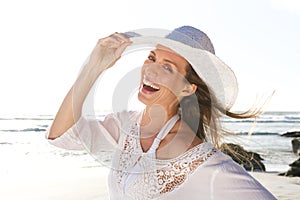 Attractive woman laughing with hat at the beach