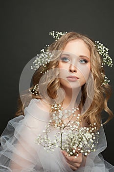 Attractive woman with long healthy blonde curly hair and flowers