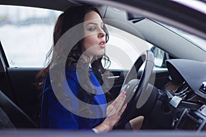 Attractive woman looks pensively into the windshield of the car