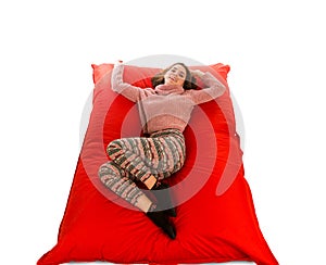 Attractive woman lying on red square shaped beanbag sofa isolate