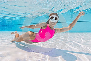 Attractive woman with mask glides underwater in swimming pool