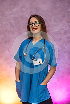 Attractive woman in medical uniform posing on abstract background. Woman doctor or nurse