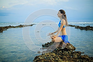 Attractive woman, meditating, practicing yoga and pranayama at the beach. Sunset yoga practice. Hands in gyan mudra. Balance and