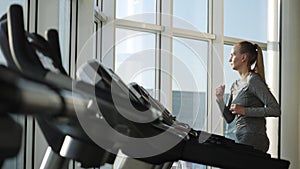 Attractive woman of middle age is running on tread mill in sport gym