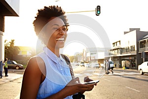 Attractive woman with mobile phone looking away and laughing