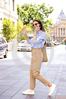 An attractive woman with mobile phone walking through the city and hailing a taxi