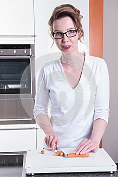 Attractive woman in modern ktchen cutting sausage