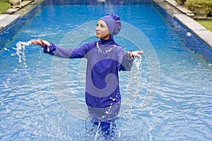 Attractive woman in a Muslim swimwear burkini splashes water in the pool photo