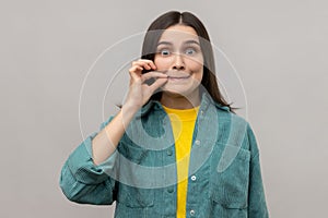 Attractive woman with mystery look making zip gesture to close mouth, keeping secret, zipping lips.