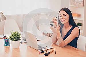 Attractive woman in office having break and doing maquillage