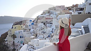 Attractive woman in Oia village looking cityscape from balcony in Santorini Island, Greece