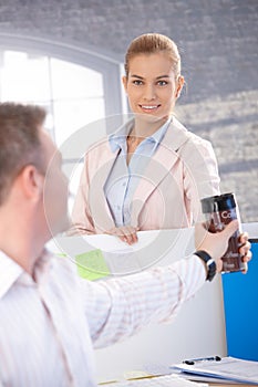 Attractive woman passing coffee to colleague