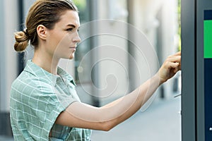 Attractive woman paying in the parking meter machine