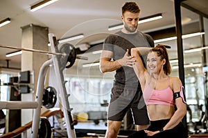 Attractive woman and a personal trainer with weight training at gym