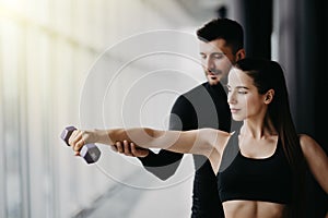 Attractive woman and a personal trainer with weight training at gym