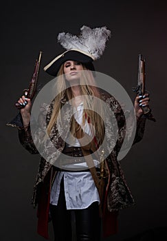 Attractive woman pirate with guns against dark background