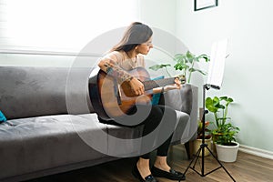 Attractive woman playing her favorite song on the acoustic guitar