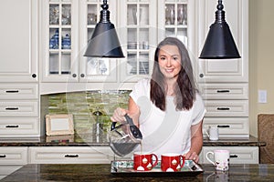 Attractive woman pouring homemade coffee for two in modern sunny kitchen