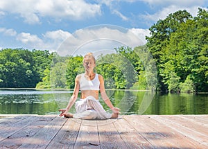 Attractive woman is practicing yoga sitting in Gomukasana exercise near lake. Young woman is meditating in Cow Face pose outdoors