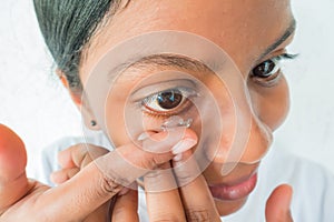 Attractive woman putting contact lenses in her eyes