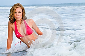 Attractive woman in red bikini splashed by wave