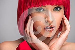 attractive woman with red hair and glittering makeup touching face